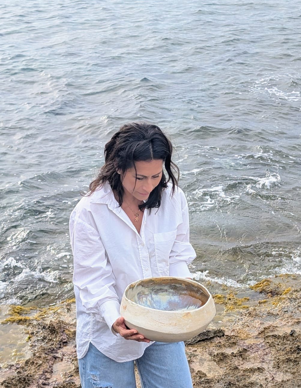 Carolina Arias vora la mar amb un bol de fang a les mans